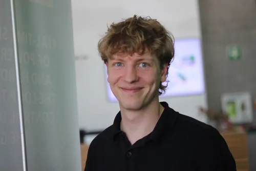 Drei Personen stehen mit Kaffeetassen im Foyer und führen ein Gespräch.