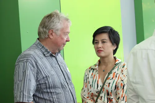 Mann mit Namensschild und Rucksack lehnt am Tresen im Veranstaltungsbereich.